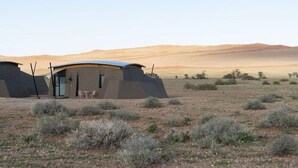 A modern, desert-style building with a flat roof and a small patio area with chairs. - The Desert Grace, Gondwana Collection Namibia (pty (Sesriem)