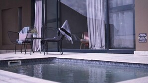 A poolside area with a seating arrangement and a sign indicating pool depth. - The Desert Grace, Gondwana Collection Namibia (pty (Sesriem)
