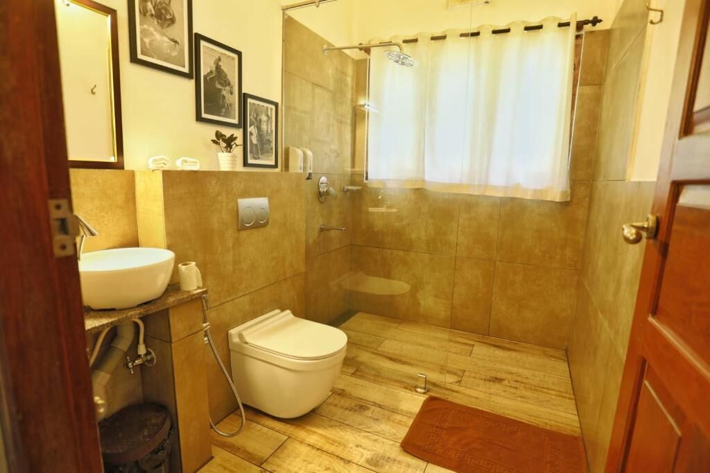 A bathroom with a toilet, sink, shower, and a wooden floor.