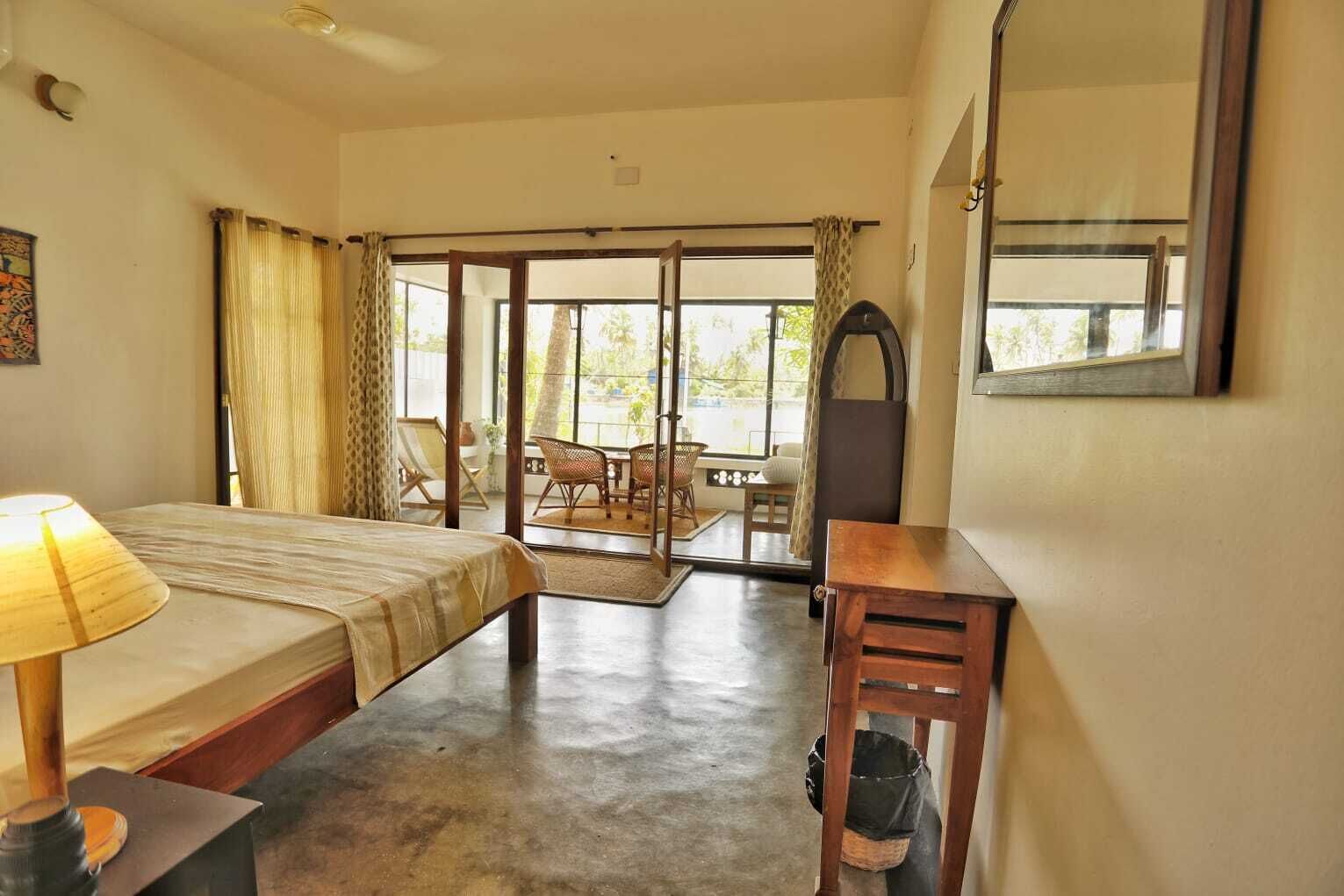 Une chambre comprenant un lit, un bureau, une chaise et donnant sur un espace extérieur aménagé avec une table et des chaises.