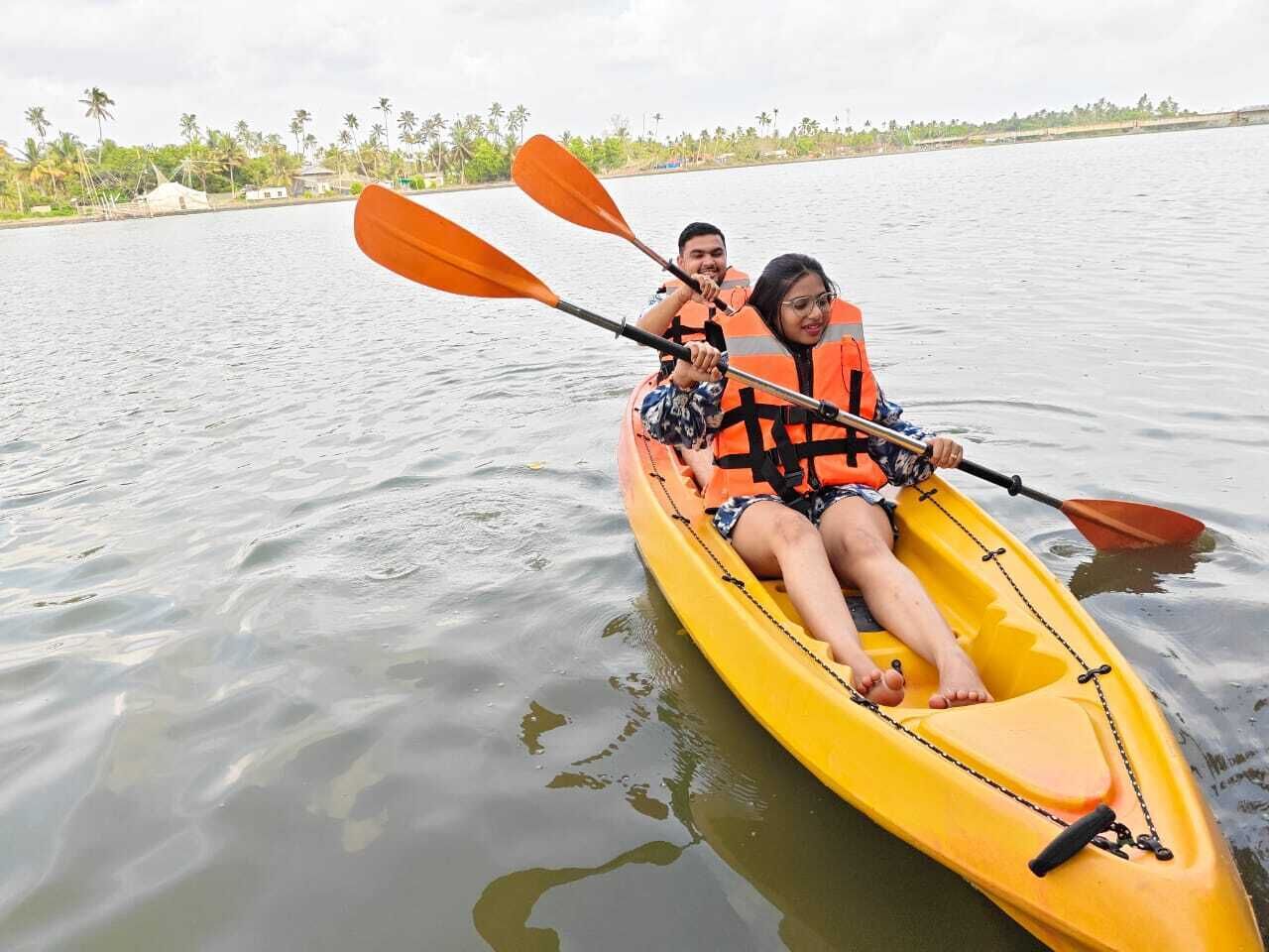 A yellow kayak on calm water with two people wearing life jackets.