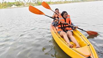A yellow kayak on calm water with two people wearing life jackets.