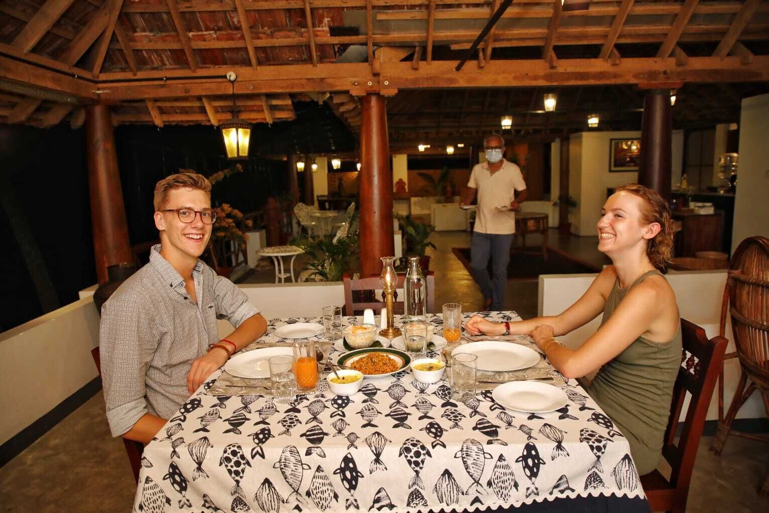 A dining area with a table set for two, featuring a patterned tablecloth and various dishes.