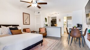 A hotel room with a bed, a desk, a chair, a ceiling fan, and a kitchenette. - Cozy Comfort Getaway North ATX Studio Convenient Easy Major City Access (Austin)