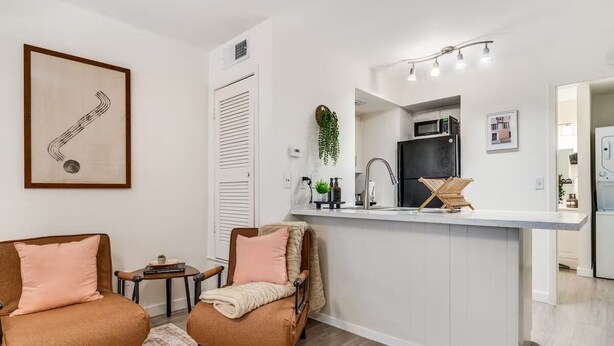 A modern kitchen with a white countertop, a black refrigerator, and a hanging plant. - Cozy Comfort Getaway North ATX Studio Convenient Easy Major City Access (Austin)