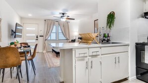 A modern kitchen with a central island, white cabinetry, and a dining area with a table and chairs. - Cozy Comfort Getaway North ATX Studio Convenient Easy Major City Access (Austin)