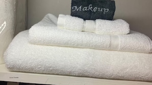 Ein Stapel weißer Handtücher, obenauf ein dunkelblaues Handtuch mit der Aufschrift 'Makeup'.