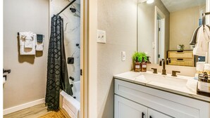 Ein Badezimmer mit Dusche, Waschbecken, Spiegel und Handtuchhalter.