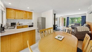 Una cucina moderna con mobili in legno, un tavolo da pranzo con sedie e un angolo salotto con divano e camino.