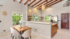A modern kitchen with a central island, wooden ceiling beams, and pendant lighting. - 4BR Tropical Retreat • Pool • Beach • Golf Cart (Playa Potrero, Santa Cruz)