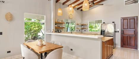 Una cocina moderna con una isla central, vigas de madera en el techo e iluminación colgante.