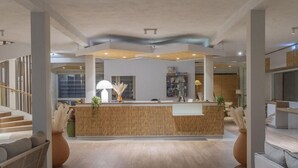 Un hall d’entrée spacieux avec un comptoir d’accueil central, un escalier et un espace détente comprenant un canapé et des fauteuils.