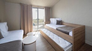Une chambre moderne et compacte, dotée d’un lit en mezzanine, d’un petit canapé et d’une table ronde.