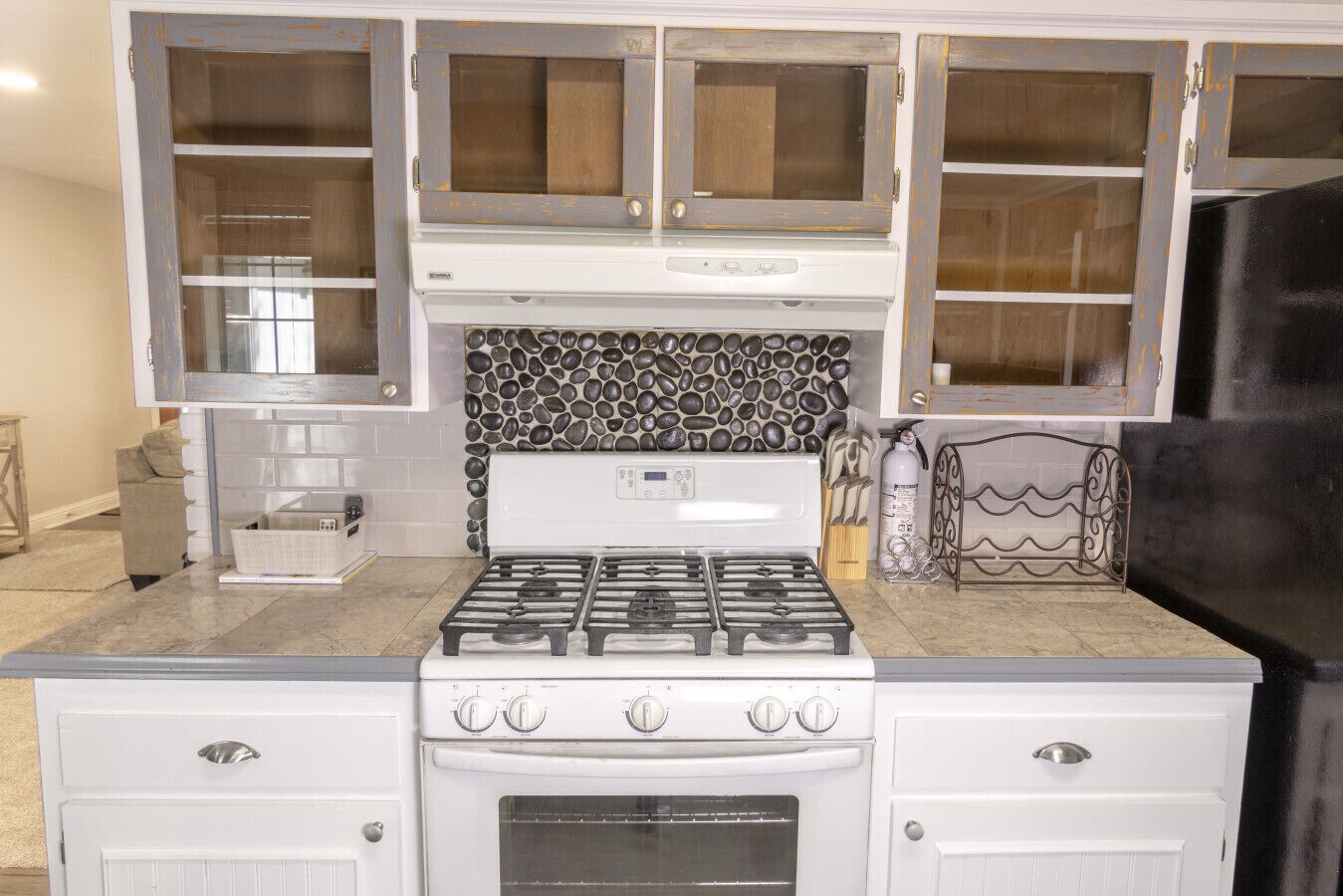 A kitchen with a gas stove, oven, and white cabinetry.
