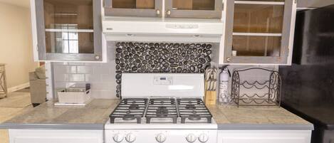 A kitchen with a gas stove, oven, and white cabinetry.