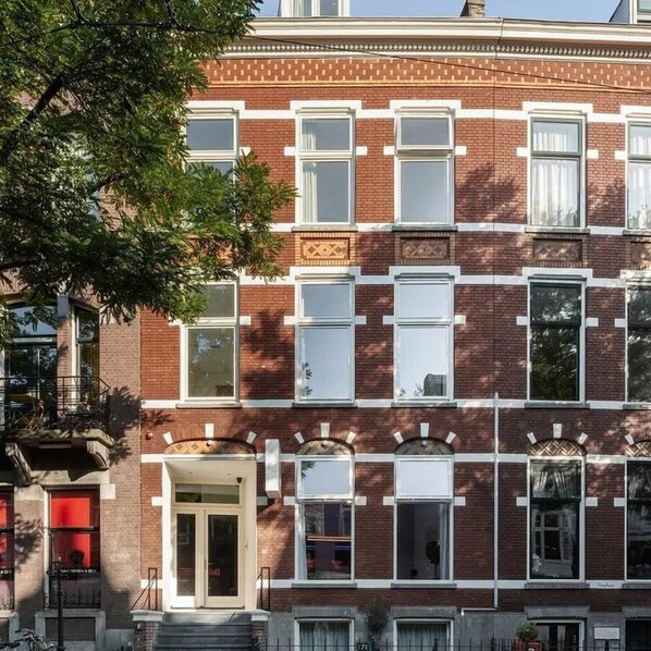 Een meerlaags bakstenen gebouw met witte raamkozijnen en een centrale ingang.