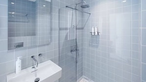 A modern bathroom with a glass-enclosed shower, a white sink, and a mirror. - 171. Urban Design Hotel (Rotterdam)