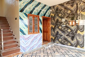 A staircase leading to a room with a marble wall and a patterned floor.