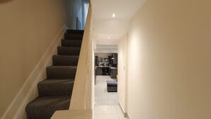 A staircase leading to a kitchen with a dining area. - Triplex Hot Tub House with Private Garden (Cardiff)