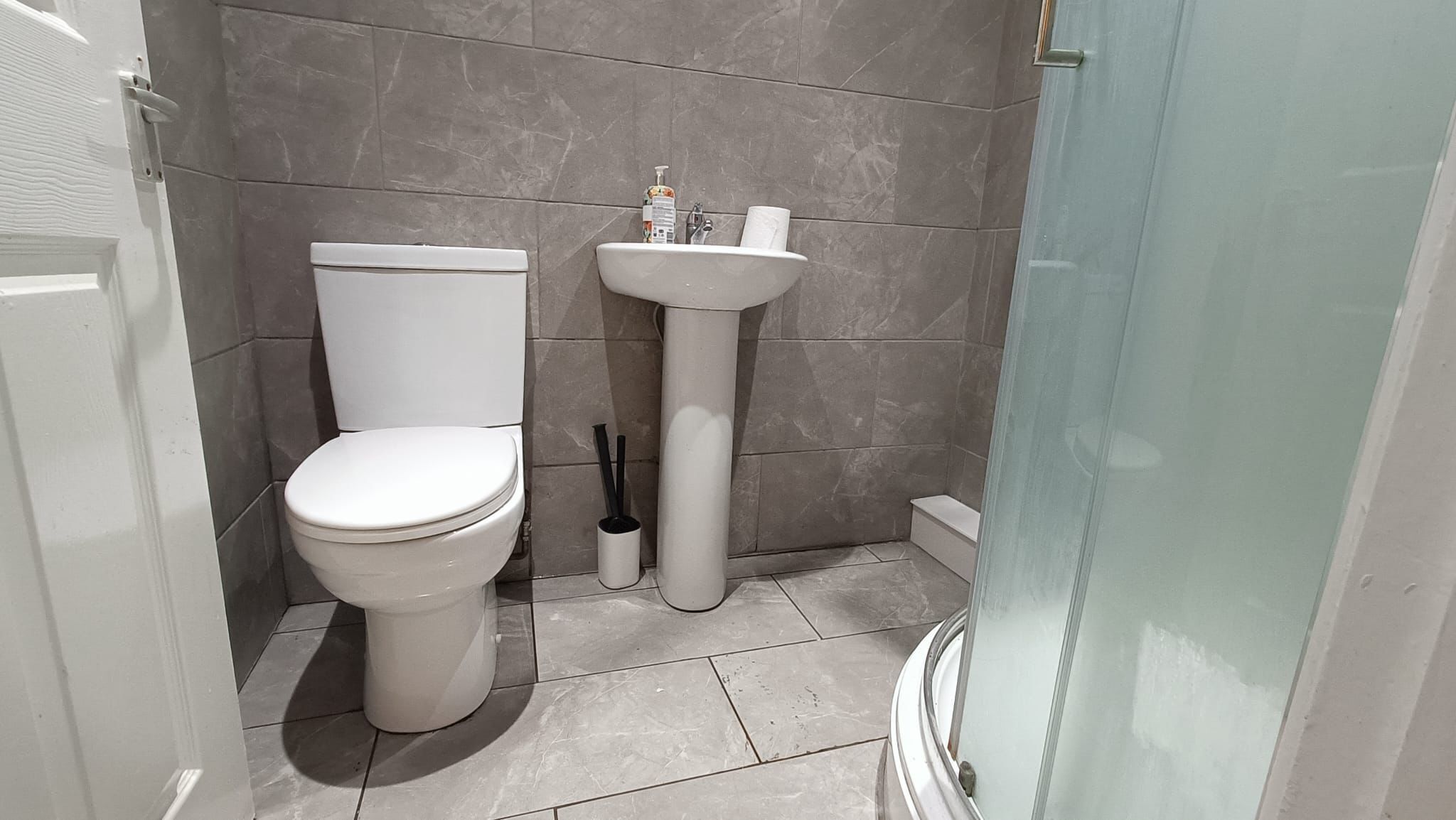 A bathroom with a toilet, sink, and shower.