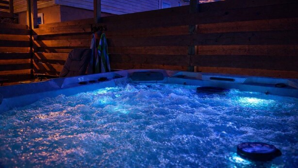 A hot tub with bubbling water, surrounded by wooden walls and a ladder. - Two Homes walk to Convention Ctr Hot Tub Game room (Branson)