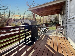 A wooden deck with a grill, outdoor seating, and a view of the surrounding landscape. - Two Homes walk to Convention Ctr Hot Tub Game room (Branson)