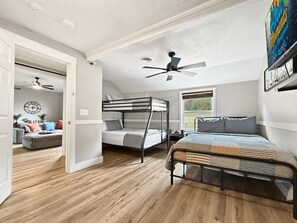 A room with bunk beds, a ceiling fan, a clock, and a window. - Two Homes walk to Convention Ctr Hot Tub Game room (Branson)