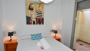 Ein Hotelzimmer mit einem Bett, zwei Nachttischen, einem Gemälde und einer Tür.