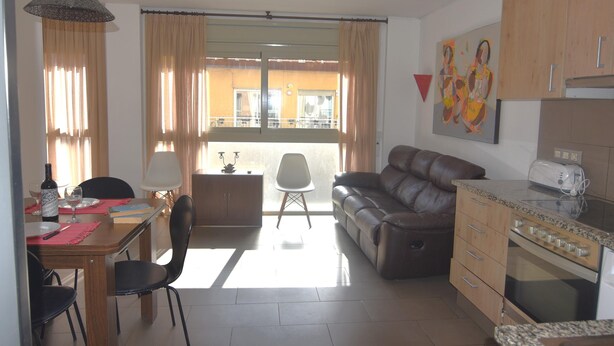 Ein Essbereich mit Tisch, Stühlen, einer Couch, einer Lampe und Blick durch ein Fenster.