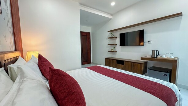 Quarto de hotel com cama, televisão, máquina de café e uma pequena cozinha.