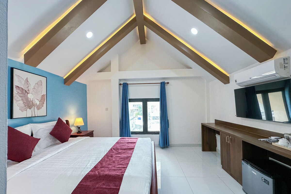 Un dormitorio con cama, escritorio, espejo y ventana con cortinas.