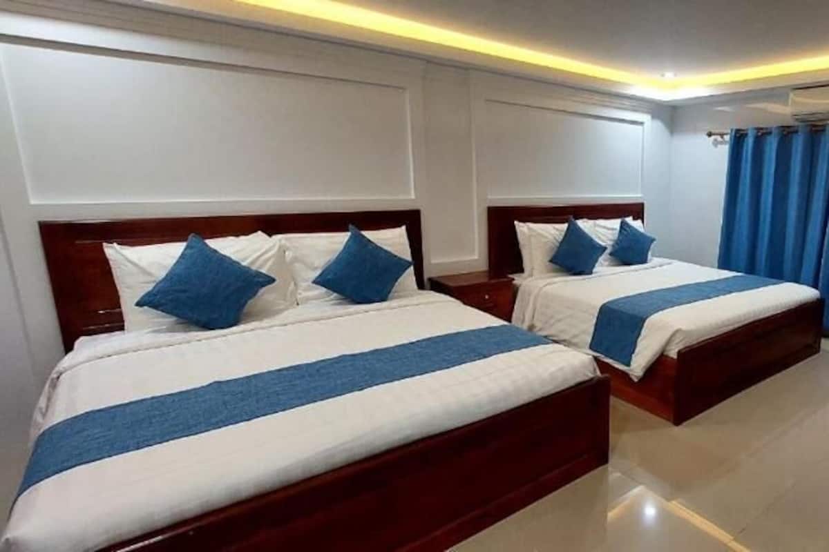 A hotel room with two beds, a desk, and a TV.
