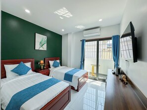 Ett hotellrum med två sängar, en TV, en luftkonditioneringsanläggning och utsikt över omgivningarna.