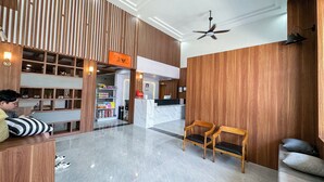 Um saguão de hotel com balcão de recepção, área de estar e ventoinha no teto.
