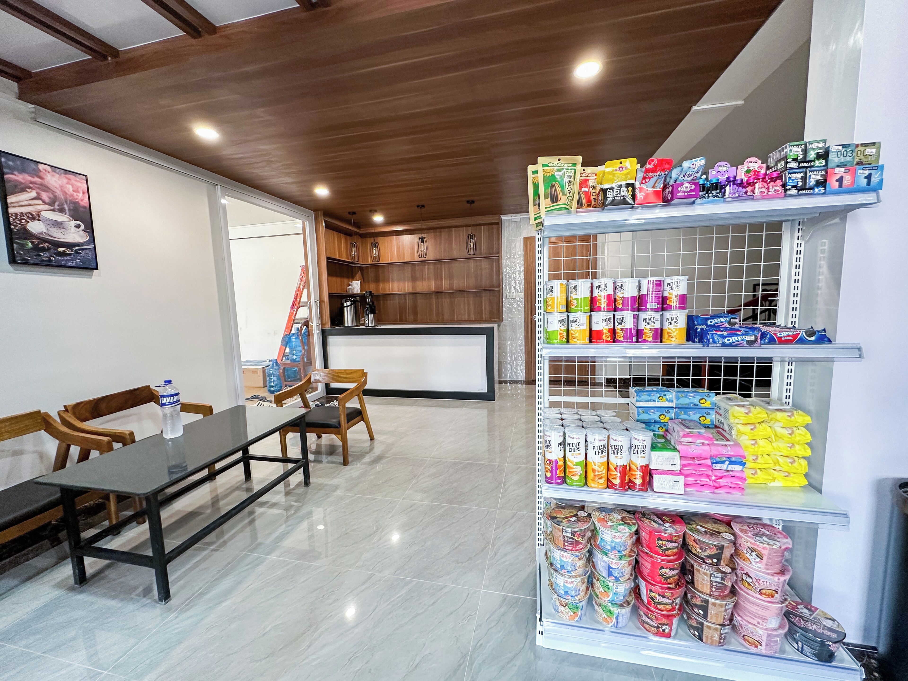 Une chambre d’hôtel comprenant un coin repas, une cuisine et une étagère remplie de collations et de produits de toilette.