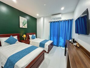 Una habitación de hotel con dos camas, un escritorio, un televisor y un equipo de aire acondicionado.