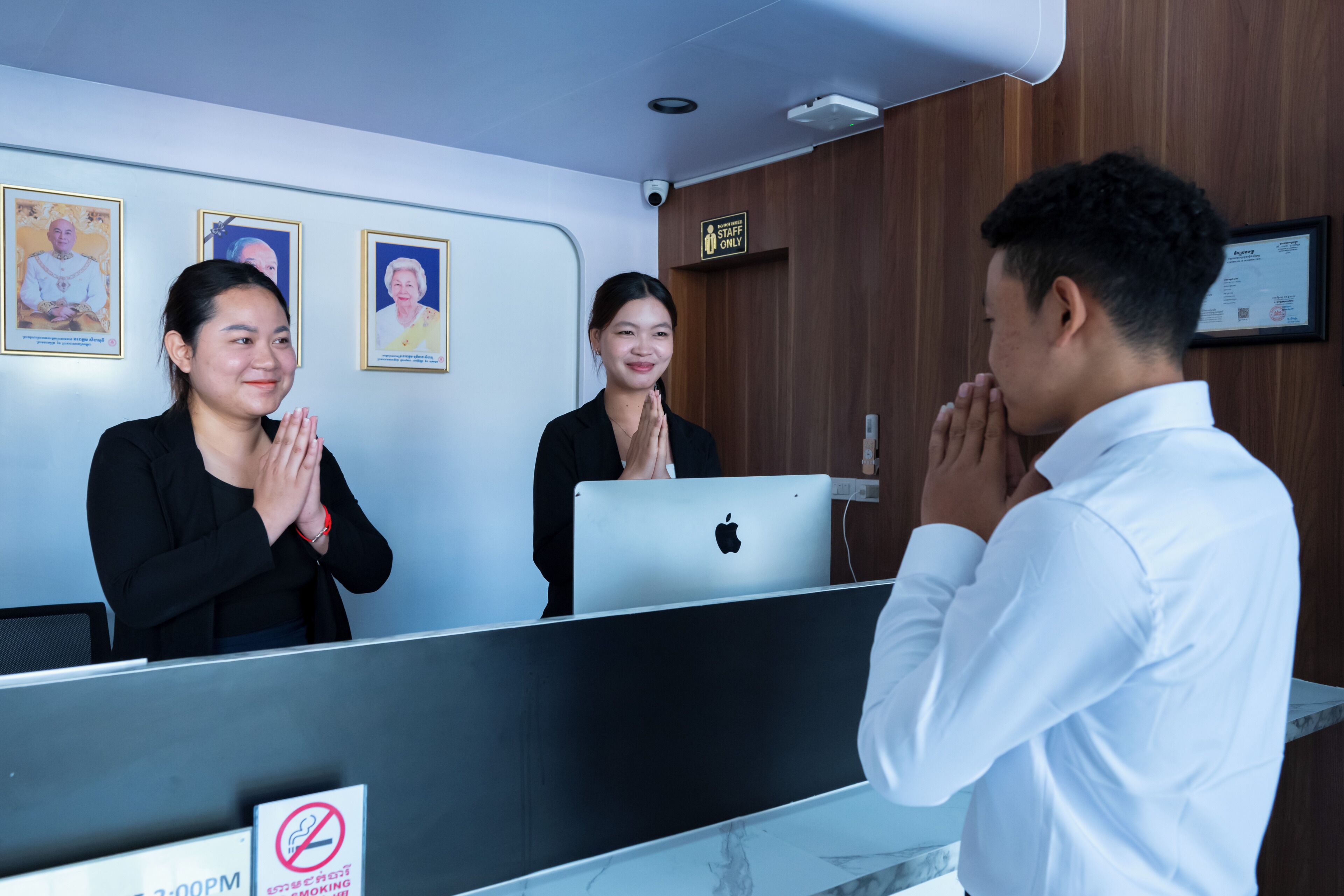 A reception desk with a computer, a 'No Smoking' sign, and framed portraits on the wall.