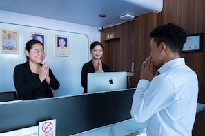 A reception desk with a computer, a 'No Smoking' sign, and framed portraits on the wall.