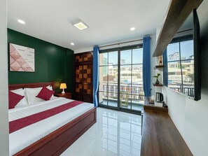 Habitación de hotel con una cama grande, vista a la ciudad desde un balcón y diseño moderno.