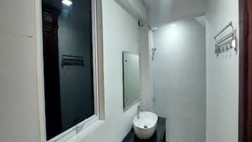 Ein kleines Badezimmer mit Fenster, Waschbecken und Dusche.