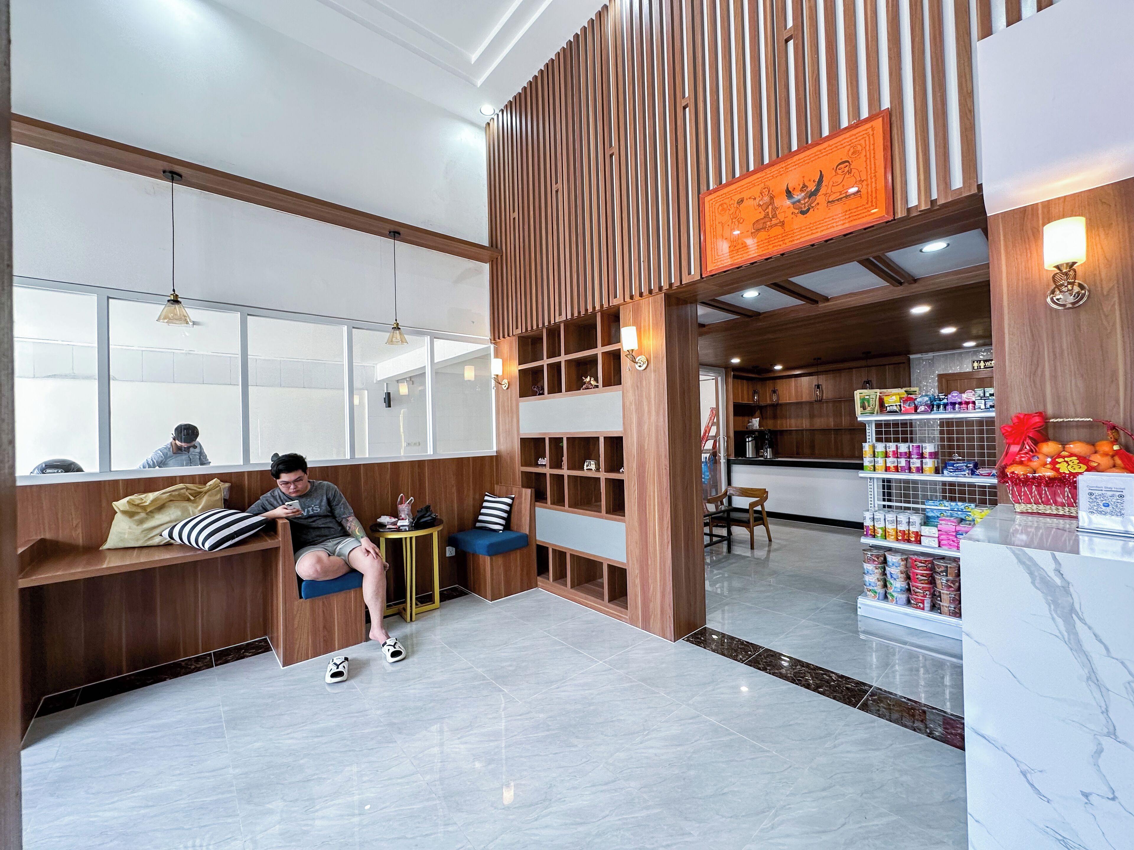 A modern interior with a reception desk, seating area, and a visible kitchen area.