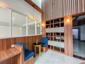Un interior moderno con un panel de madera, un banco acolchado azul, una pequeña mesa redonda y un estante montado en la pared con objetos decorativos.