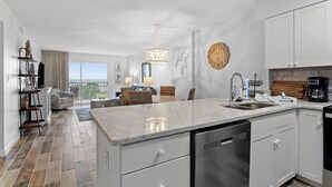 Cozinha moderna com uma ilha grande, armários brancos e vista para o exterior.