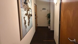 Ein Korridor mit Holzboden, einer Tür rechts und einem an der Wand befestigten Kunstwerk links.