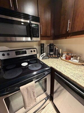 A kitchen with a stove, microwave, coffee maker, and cabinets. - Smokehouse 409 (Richmond)
