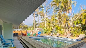 Uma área de piscina com deck de madeira, espreguiçadeiras e céu azul límpido.