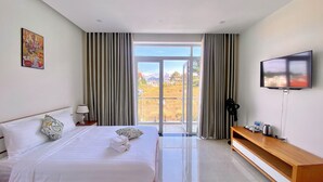 Habitació d'hotel amb llit, televisió, escriptori i finestra amb cortines.