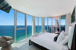 A modern hotel room with a large bed, a view of the ocean, and a cityscape in the background. - Luxury 3-Bedroom Sky Home | 49th Floor Ocean Views | Hilton Surfers Paradise (Surfers Paradise)