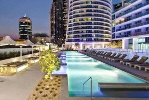 A rooftop pool with lounge chairs, surrounded by modern buildings. - Hiltons Ocean Crown 49 (Surfers Paradise)