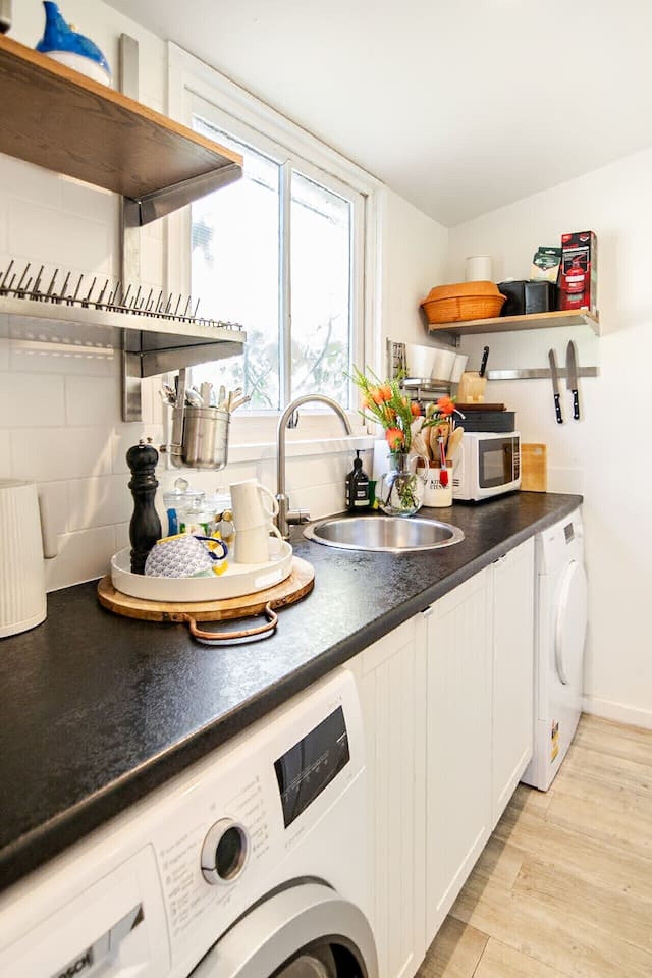 A compact kitchen with a washing machine, a microwave, and a sink.